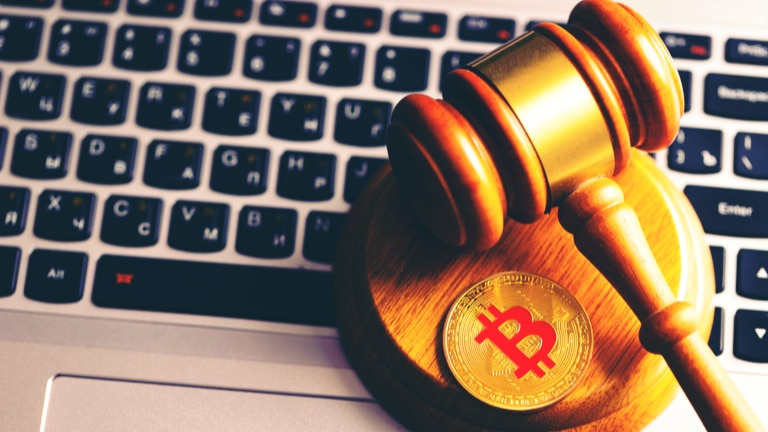 judge gavel and bitcoin sitting on top of a laptop